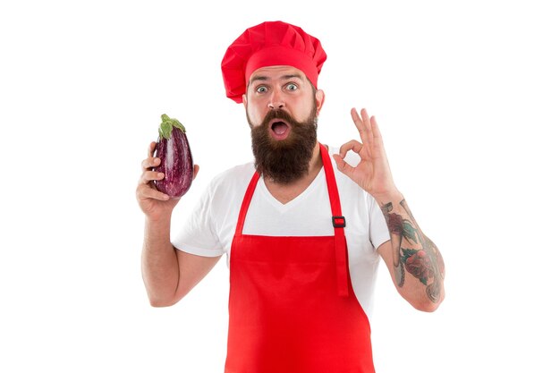 OK, het is biologisch. Bebaarde man houdt biologische aubergine geïsoleerd op wit. Chef-kok die natuurlijk biologisch voedsel kookt. De beste biologische keuze.