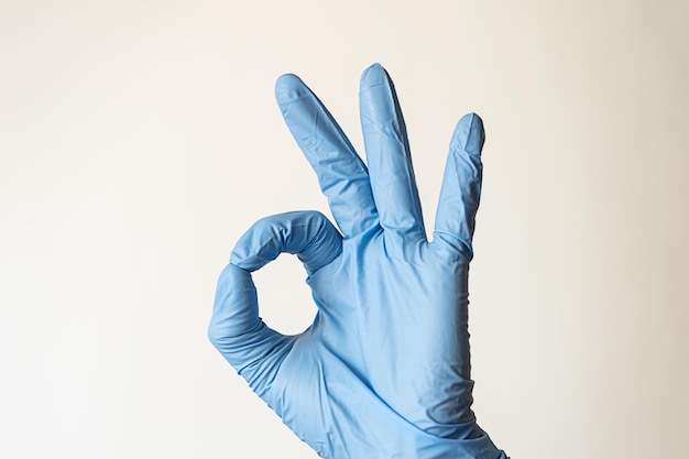 Ok sign is showed by left man hand in a blue medical glove