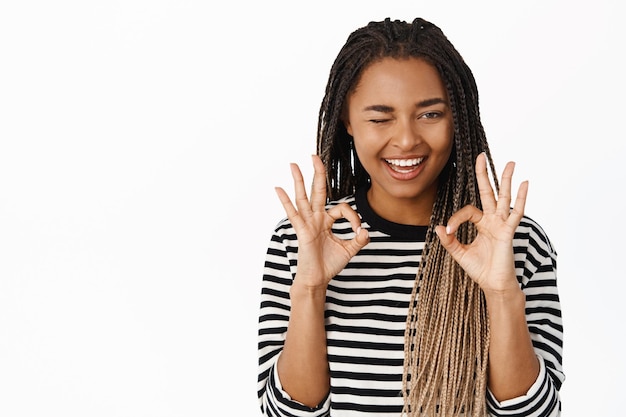 Okay excellent Smiling black girl winking showing okay sign and looking pleased recommending smth white background