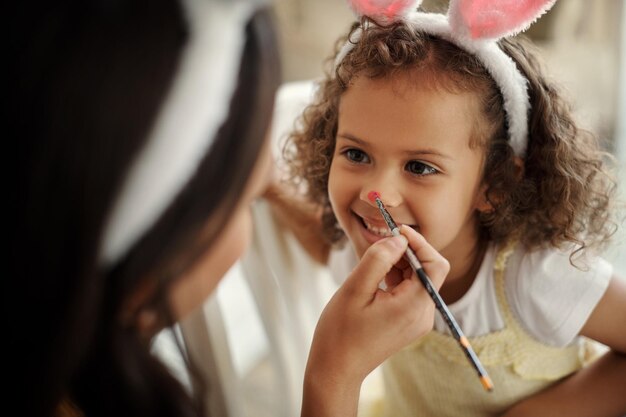 Okay stay still for me shot of a woman painting her daughters face during the easter holiday