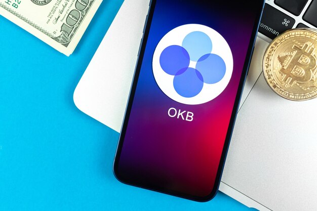 OKB munt symbool. Handel met cryptocurrency, digitaal en virtueel geld, bankieren met concept voor mobiele telefoons. Zakelijke werkruimte, tafel met laptop bovenaanzicht foto