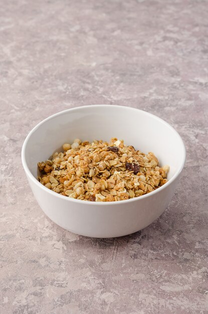 Okkernootgranola in witte kom op grijze achtergrond