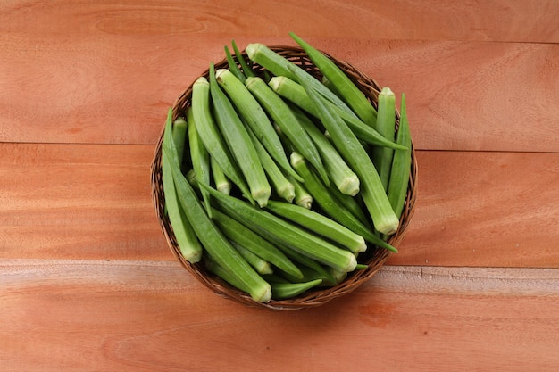 Okra or Ladys finger or Bhindi fresh green vegetable arranged  in a basket with wooden textured backgroundisolated and selective focustop view