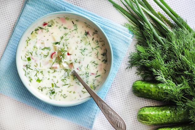 Okroshka  traditional Russian cold soup with fresh cucumber boiled eggs and dill Flat lay top view