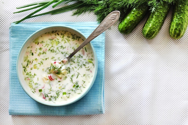 Okroshka  traditional Russian cold soup with fresh cucumber boiled eggs and dill Flat lay