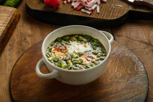 Okroshka in a tureen with kvass, decorated with egg and sour cream. Horizontal photo