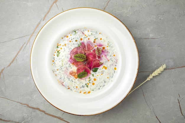 okroshka with radishes cucumbers herbs and yogurt on a gray table