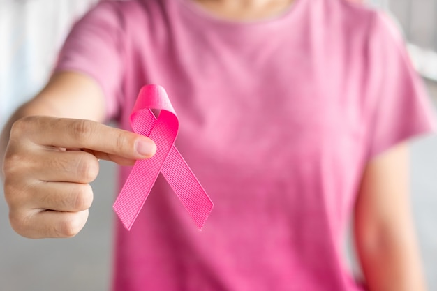 Oktober Borstkanker maand, Vrouw in roze T-shirt met hand met roze lint voor het ondersteunen van mensen die leven en ziekte. Gezondheidszorg, Internationale Vrouwendag en Werelddag voor kanker