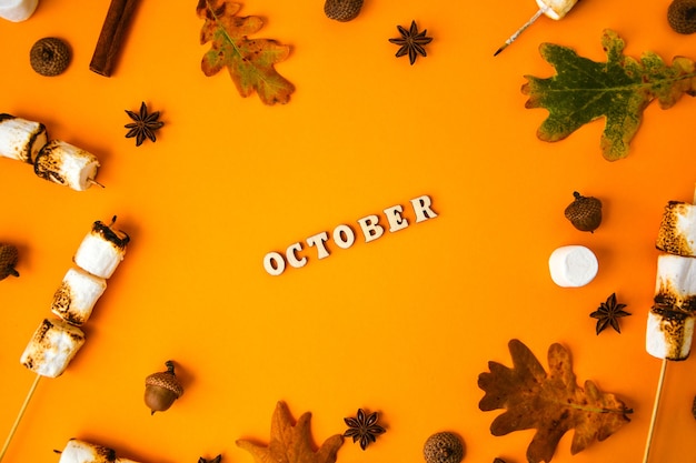 OKTOBER tekst. Kaneel marshmallows bladeren en anijs op gele achtergrond. Herfst samenstelling. Patroon gemaakt van herfst dingen. Plat leggen. Ornament Voor Dankzegging. Herfst Frame met kopie ruimte.