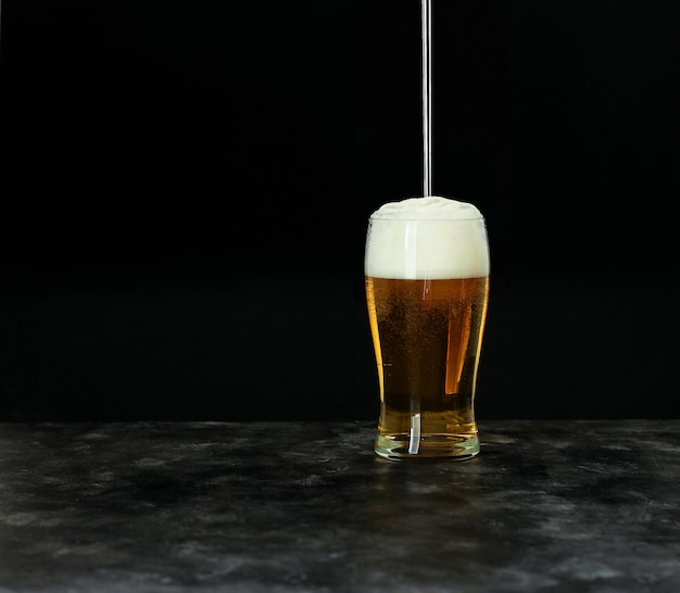 Oktoberfest beer festival concept. Cold beer with foam in glass on dark , copyspace.