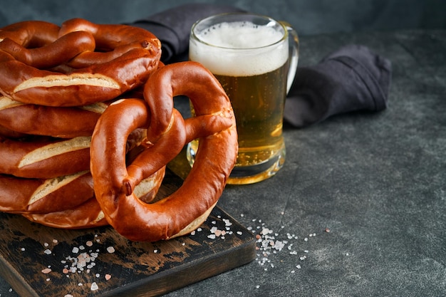 Photo oktoberfest concept card traditional bavarian pretzels with beer bottle mug on old dark black rustic background perfect for octoberfest oktoberfest food menu