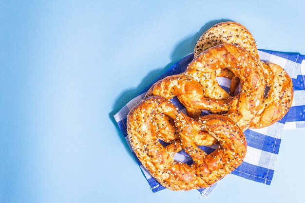 Oktoberfest concept - pretzels op een traditioneel servet. Trendy hard licht, donkere schaduw. Pastelblauwe achtergrond, bovenaanzicht