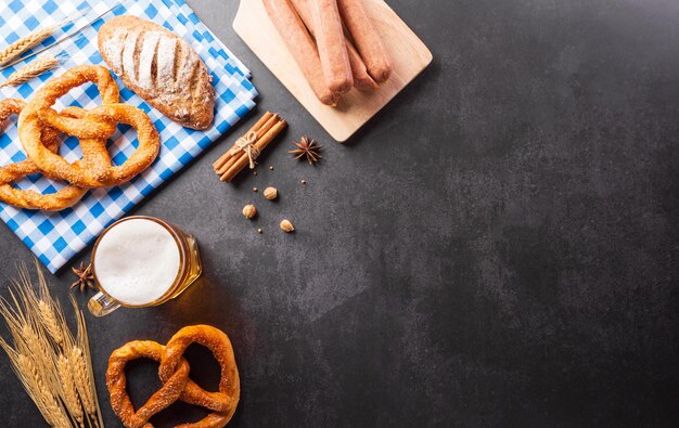 Oktoberfest festival decoratie symbolen gemaakt van pretzel brood bierworst chips en Beierse witte en blauwe stof op donkere stenen achtergrond