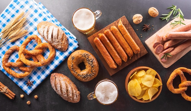 Oktoberfest festival decoration symbols made from Pretzel loaf beer sausage potato chips and Bavarian white and blue fabric on dark stone background