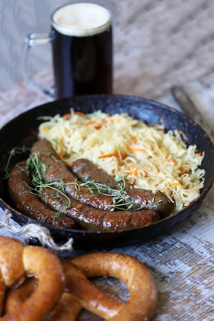 Пища октоберфест. горячие баварские колбаски с квашеной капустой в сковороде. вкусная пивная фестивальная еда
