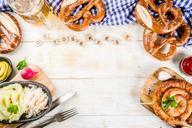 Oktoberfest food menu, bavarian sausages with pretzels, mashed potato, sauerkraut, beer bottle and mug, white wooden table top view