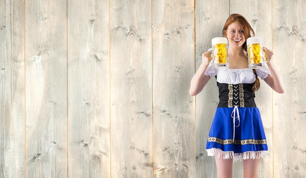 Photo oktoberfest girl holding jugs of beer against pale wooden planks