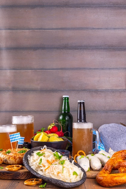 Photo oktoberfest munich traditional festival menu foods bavarian sausages pretzels potato sauerkraut beer bottle and mug background flier for oktoberfest invitation on old wooden table copy space