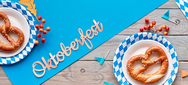 Oktoberfest, panoramische plat lag op houten tafel met met blauw papier en pretzels op blauw wit papieren borden