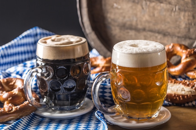 Oktoberfest two beer with pretzel wooden barrel and blue tablecloth.