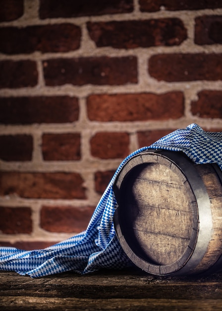 Oktoberfest wooden barrel and blue tablecloth on rustic oak table.