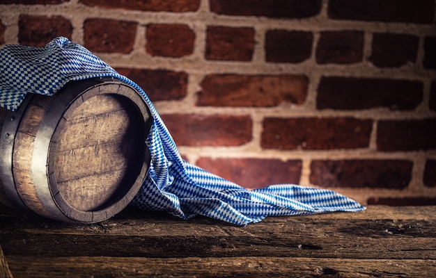 Oktoberfest wooden barrel and blue tablecloth on rustic oak table.