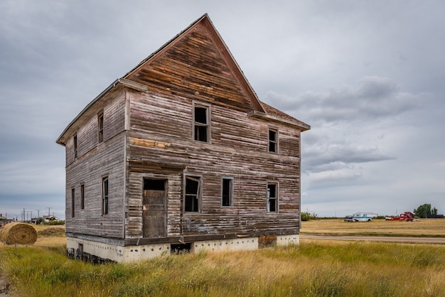 An old abandoned home and classic trucks in background in Canadian ghost town