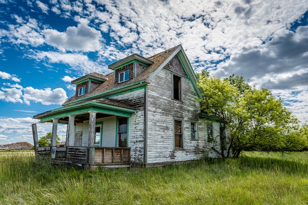 Old, abandoned prairie farmhouse with trees