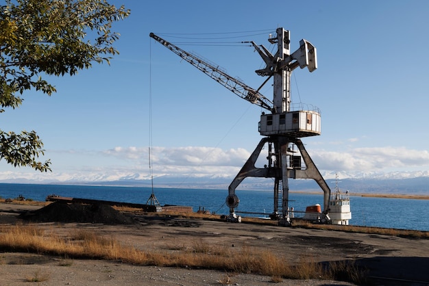 Old abandoned soviet crane in port balykchy on issykkul lake at sunny autumn afternoon