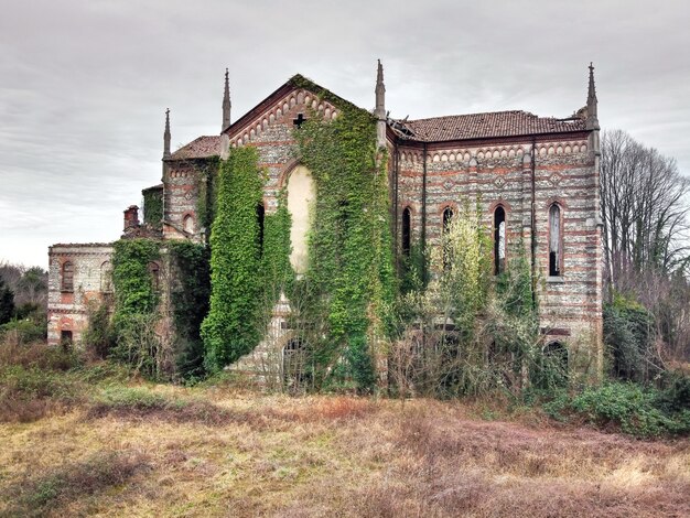 Old abandoned stone church overgrown with weeds