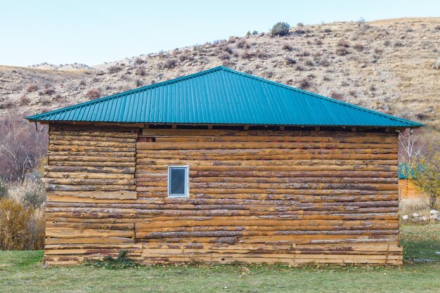 Old abandoned wooden house made of slab under a blue metal roof in Kazakhstan