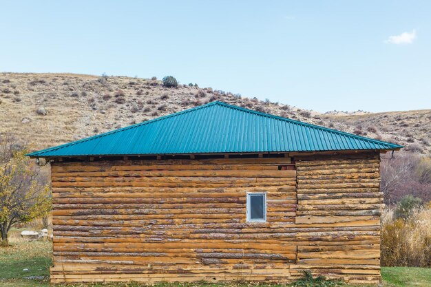 Foto vecchia casa in legno abbandonata fatta di lastre sotto un tetto di metallo blu in kazakistan