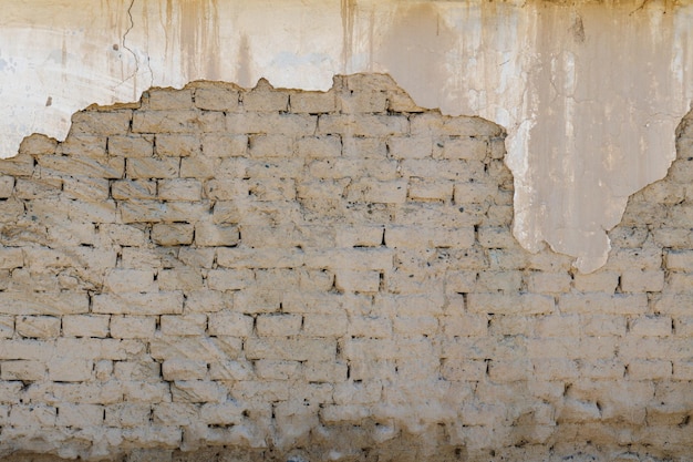 Old adobe building wall with peeled off plaster