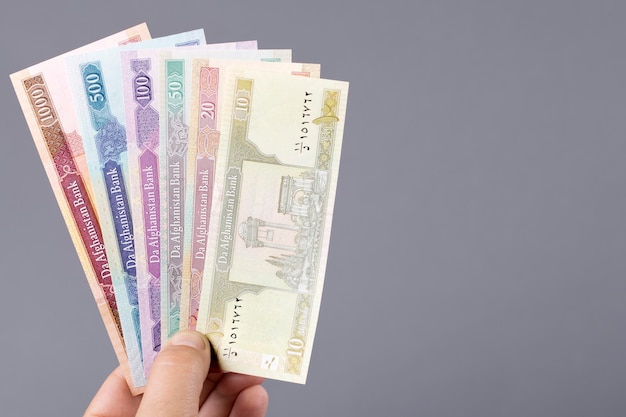 古いアフガニスタン貨幣 アフガニが手に灰色の背景に