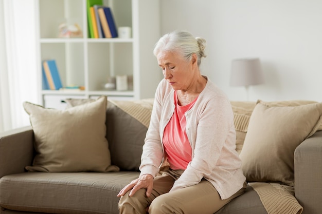 Photo old age health problem and people concept senior woman suffering from pain in leg at home