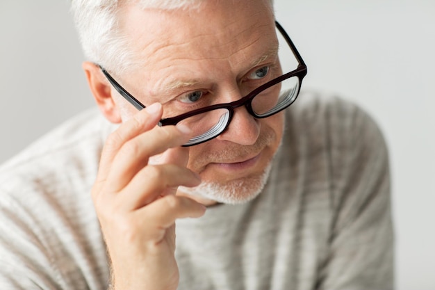 old age, problem and people concept - close up of senior man in glasses thinking