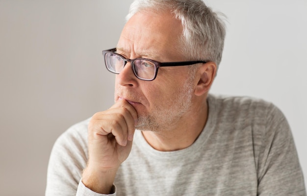 old age, problem and people concept - close up of senior man in glasses thinking