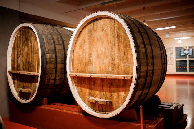 Old aged traditional wooden barrels with wine in a vault lined up in cool and dark cellar in Italy, Porto, Portugal, France