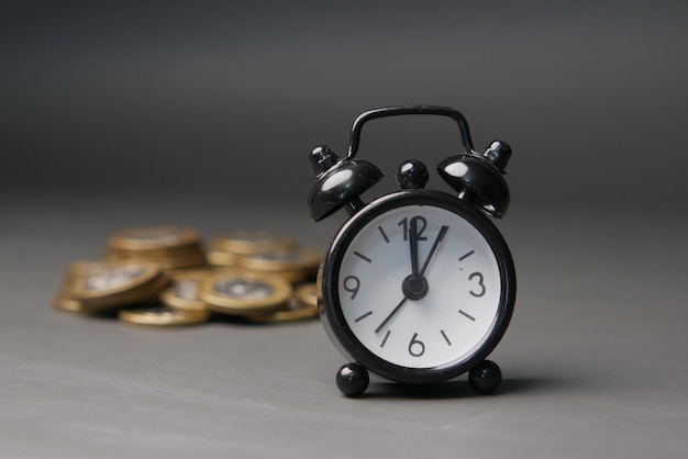 Old alarm clock and coins on black background