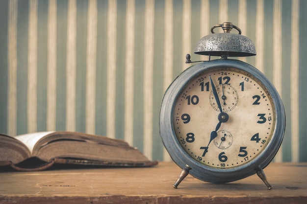 An old alarm clock and an open book