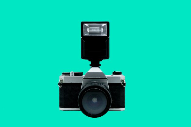 Foto vecchia fotocamera analogicainstallato il flash con la fotocameralo sfondo è liscionero e grigioxaci sono segni di usura sulla fotocamera