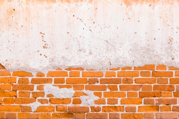 An old ancient wall made of red brick and painted over with mortar.