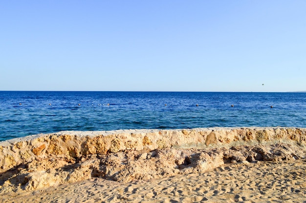 오래된 고대의 노란 돌 울타리 모래와 푸른 소금 바다 바다로 덮인 강모 조약돌로 만든 울타리 울타리