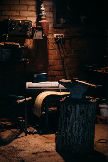 Photo an old anvil attached to a wooden base stands in a private blacksmiths workshop.