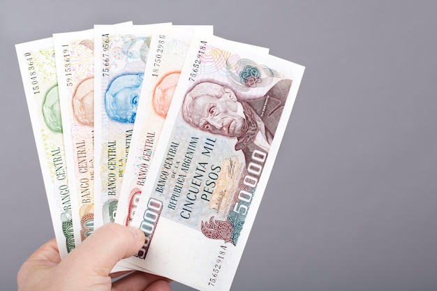 Old Argentine peso in the hand on a gray background