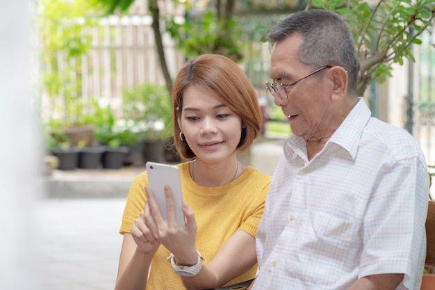 Old Asian father and daughter. Daughter teaches an elderly father to use a mobile phone