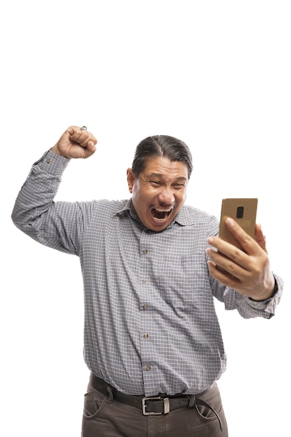 Old asian man celebrating his success while holding a phone with fist pump gesture white background