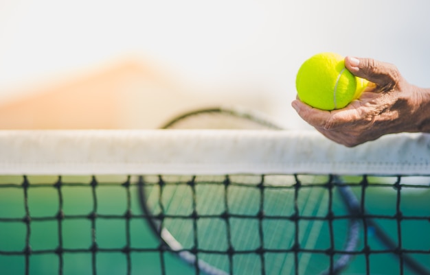 old asian man hold two tennis balls in left hand