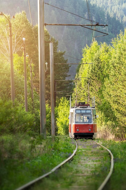 An old atmospheric tram in the forest against the background of mountains an interesting colorful ro