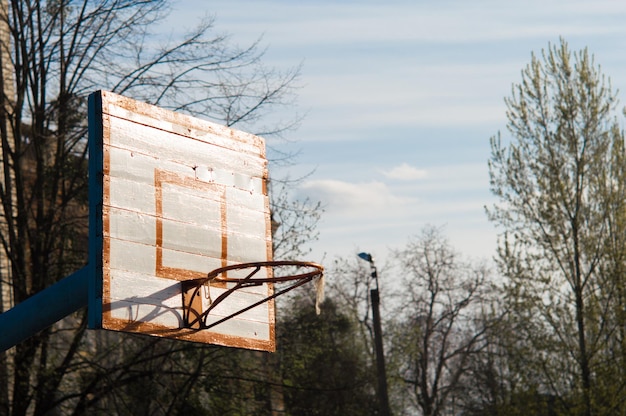 Old basketball hoop with a wooden board iron basketball hoop in\
the school stadium can be used like a wallpaper or postcard